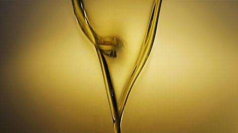Slow motion shot of motor oil pouring on yellow light background. 
