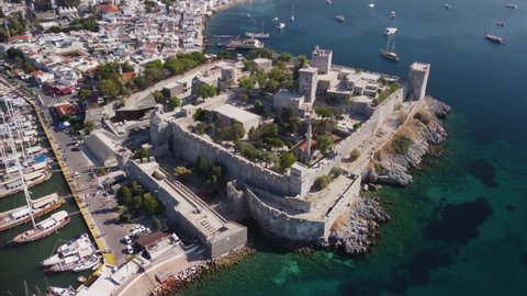 Bodrum, Turkey - October 18, 2021: Awesome aerial view of Bodrum Castle. Drone flying over the castle and the sea. Bodrum Harbor and the port city are visible on scenic mountains background.