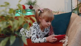 Caucasian worried excited little teen child girl enthusiastically playing shooter video online games on mobile phone. School toddler kid using smartphone gadget app with racing simulator at home alone