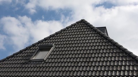 Roof window in velux style with black roof tiles.
