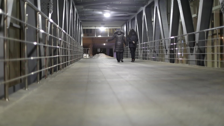 Bridge across road. Pedestrian area. Light in tunnel. Man walks inside tunnel.