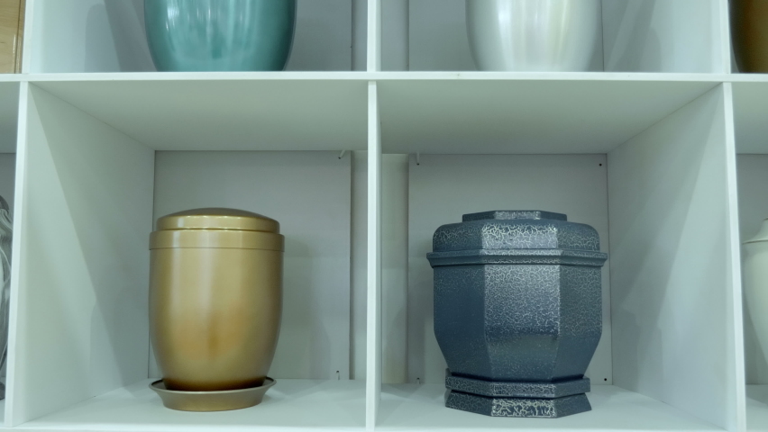 Various vases for the ashes of the dead at the exhibition of funeral services. Close up. Shot in motion Royalty-Free Stock Footage #1090323691