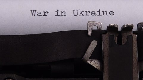 Typing phrase "War in Ukraine" on retro typewriter.