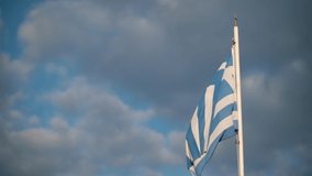 Greek flag rippling on the wind against cloudy sky, Santorini, Greece