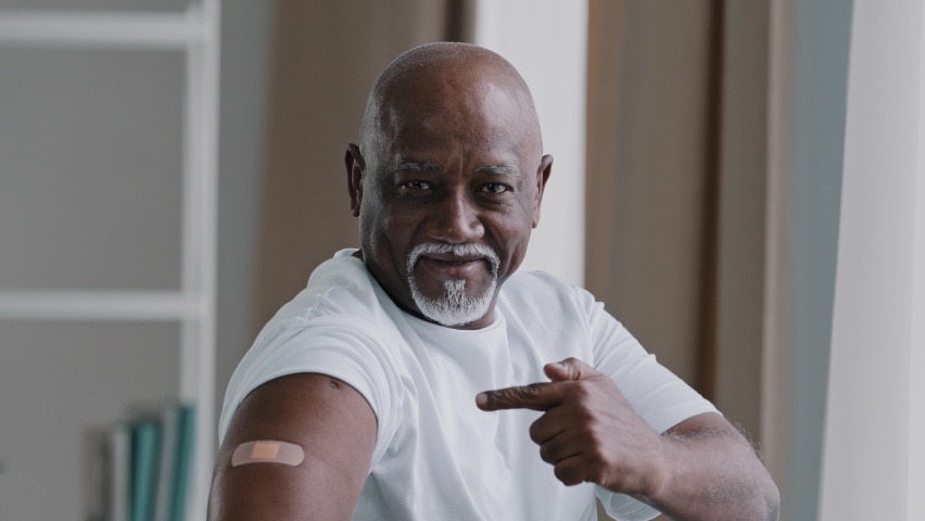 Portrait african american old senior mature man patient shows medical plaster on shoulder demonstrates injection mark satisfied male client after vaccination with covid-19 virus vaccine antivirus dose | Shutterstock HD Video #1090324779