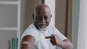 Portrait african american old senior mature man patient shows medical plaster on shoulder demonstrates injection mark satisfied male client after vaccination with covid-19 virus vaccine antivirus dose - Powered by Shutterstock - Get 15% off with code: PIKWIZARD15