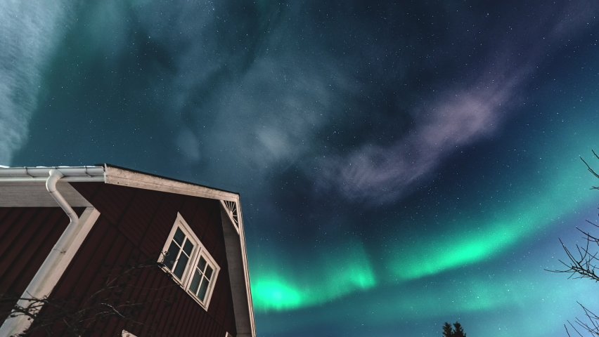 Panning time lapse video on starry night sky with mild green Aurora Borealis lights at horizon light. Traditional wooden Swedish red house with tiny clouds | Shutterstock HD Video #1090326861