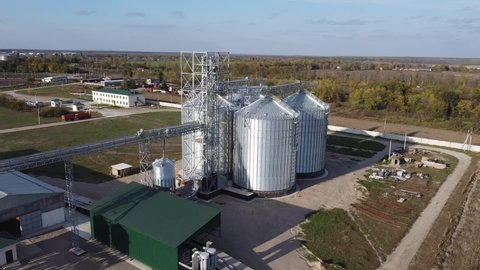 Aerial view of granaries. Grain storage and processing plant in countryside. Chrome colored granaries and buildings. Grain storage bins and other agricultural facilities in rural area