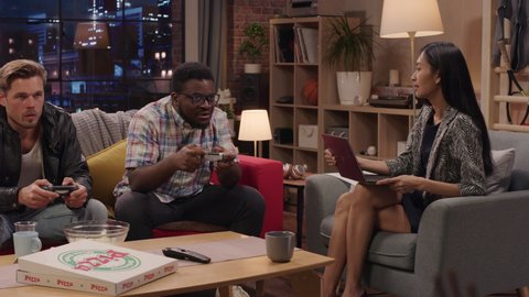 Television Sitcom: Four Diverse Friends having Fun in the Living Room. Funny TV Show Girls Reading and Working, Guys Playing Video Games on a Couch. Comedy Series on Network Channel, Streaming Service