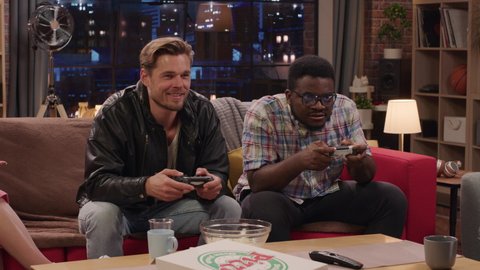 Television Sitcom: Four Diverse Friends having Fun in the Living Room. Funny TV Show Guys Playing Video Games on a Couch. Comedy Series on Playback Channel, Streaming Service Broadcast