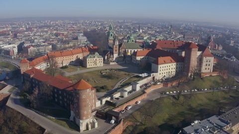 Drone camera moves away from  castle on Wawel hill, panoramic view of busy urban city Krakow Poland in the morning fog. Aerial video footage. beautiful historical landmark