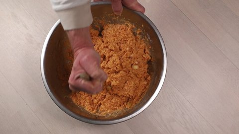 A cook mixes a batch of potatoes, lentils, and spices to make vegetarian meatballs.
