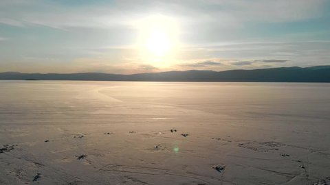 Drone view of the frozen Lake Baikal at sunset. Beautiful spring landscape.