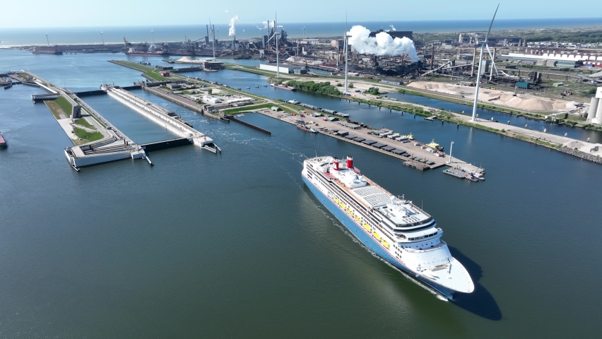 4k aerial video of cruise ship leaving large sea sluice towards Amsterdam in the Netherlands. Tata steel factory in the back ground