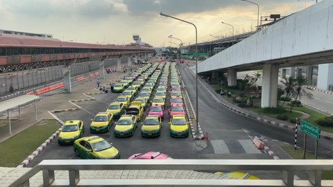 BANGKOK, THAILAND - Circa January, 2022 : Taxis cab line up outside Don Mueang International Airport. Cars park muster in row at parking lot with no passengers. Travel restriction lockdown concept