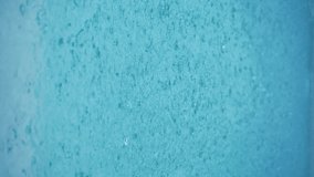 Vertical video - Rain Water Droplets Splash into a Blue Puddle. Slow motion close up of rain hitting a puddle during a storm in rainy season