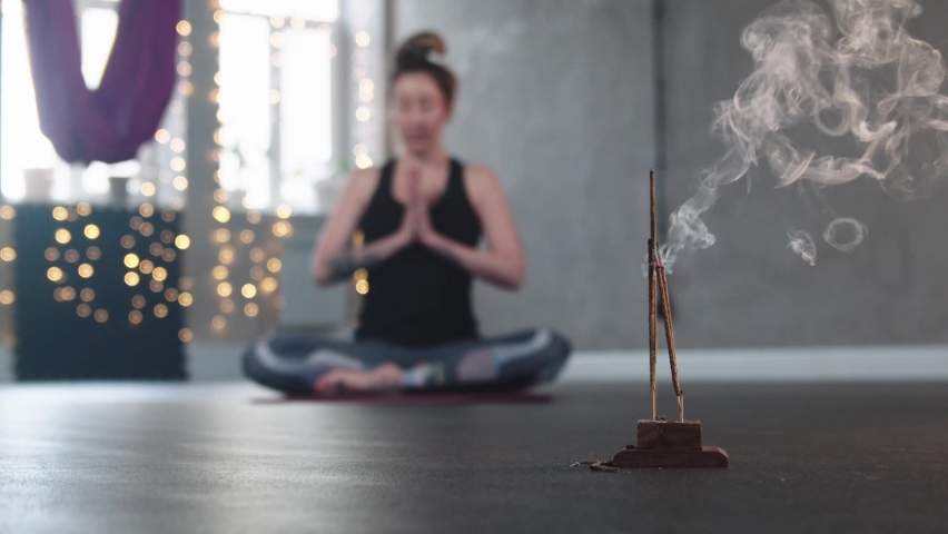 Smoldering incense in the studio - a woman meditating on the background Royalty-Free Stock Footage #1090337161