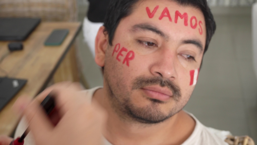 close-up painting the face of a man with the flag of Peru and the phrase "let