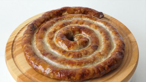 Hot homemade sausage lies on the cutting board. Sausage on a wooden board. Barbecue meat dishes Grilled sausages, homemade fresh sausage spinning on a plate.