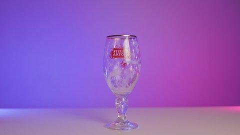 SEOULD, KOREA, SOUTH - Dec 25, 2020: A person pouring fresh beer in a Stella Artois glass on a gradient purple background