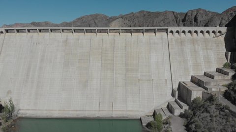 A drone video over the reyunos dam in Mendoza, Argentina. A sunny day, a blue lake and a huge dam.