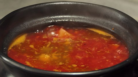Large hot pot of homemade red borscht. A variant of beet, tomato, and cabbage soup. Borscht is boiling in a saucepan on the stove.
