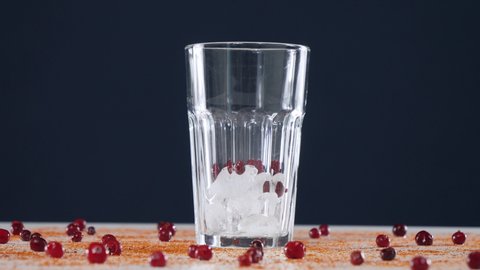 Add cranberries to a glass of ice on a blue background