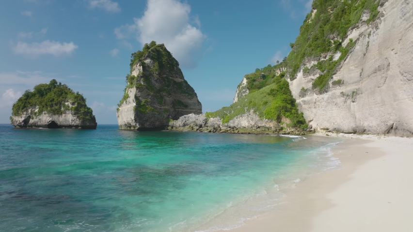 Fit tourist woman in black bathing suit running along turquoise water of Diamond beach, Nusa Penida