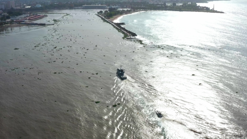 Armed ship navigating at sunrise on Caribbean sea towards Santo Domingo coast in Dominican Republic. Aerial backward