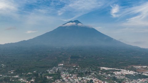 Aerial hyperlapse of Volcan de Agua in Antigua Guatemala with clouds hovering around the top