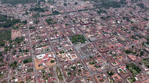 Aerial hyperlapse flying over and mountain to see downtown historic Antigua, Guatemala.