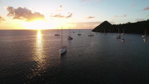 Yachts parked near Pigeon Island, Saint Lucia, lit up by a beautiful golden sunset.