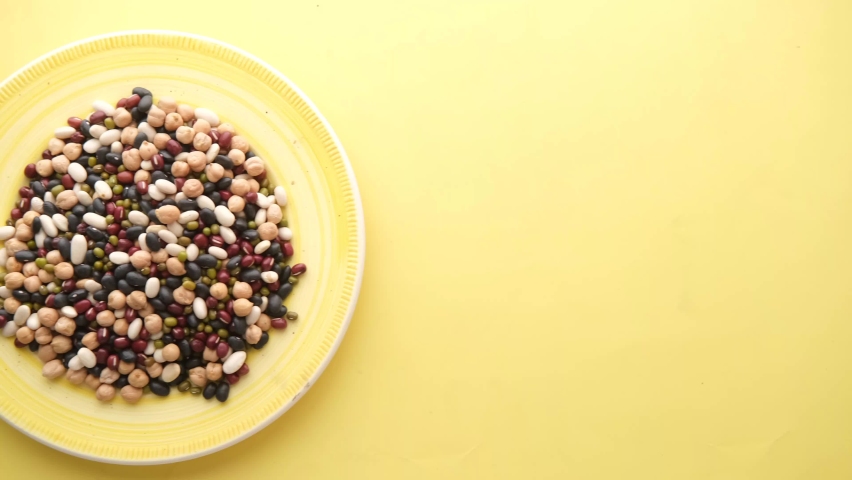  top view of mixed beans on a plate on yellow background 
