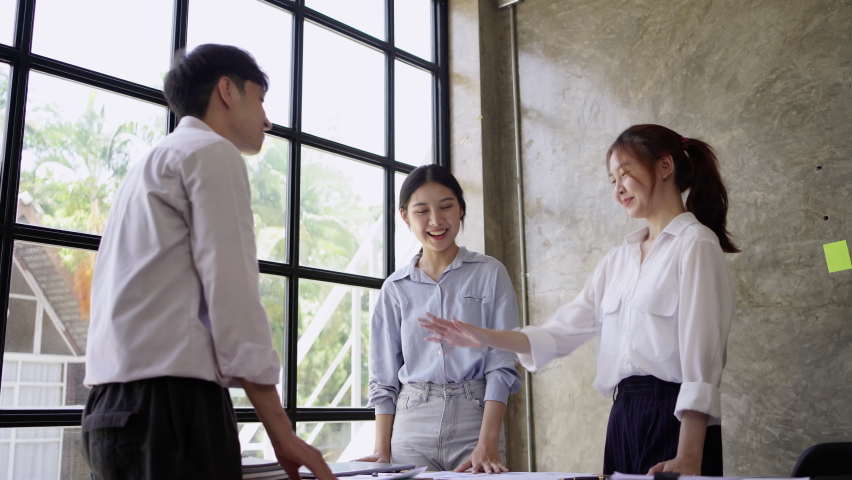 Group of young Asian people smiling happy standing putting hands together and giving high five at the office. Unity and teamwork concept. Royalty-Free Stock Footage #1090351767