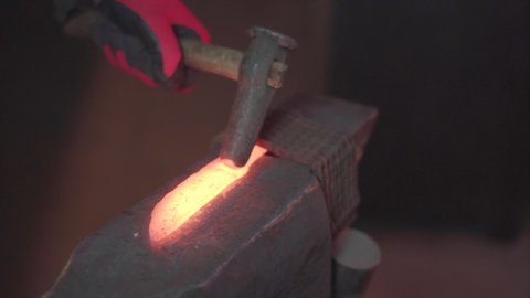 Blacksmith manually forging molten metal in smithy workshop. Damascus steel knife.