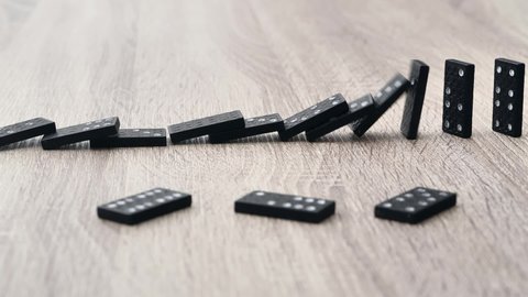 Domino effect in slow motion - falling black tiles with white dots. Dominoes falling in line effect business concept