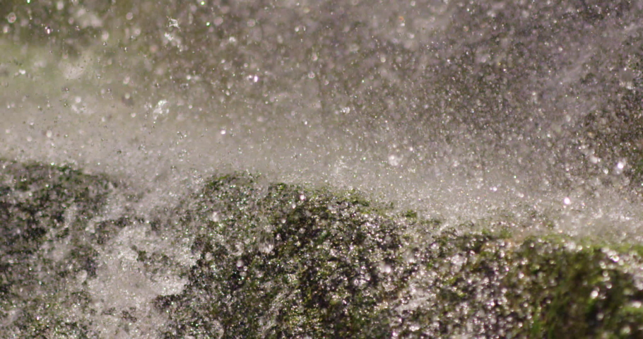 Close up view at a waterfall water droplets and spray flowing and splashing on rocks. Above waterfall angle. Outdoor, nature concept. | Shutterstock HD Video #1090360539