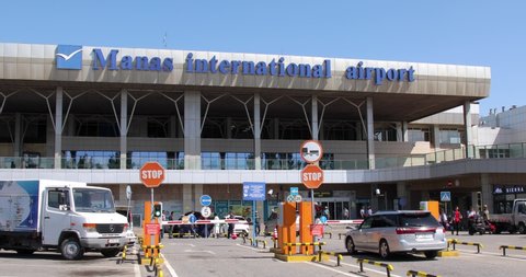 Bishkek, Kyrgyzstan - May 13, 2022: Manas International Airport exit with taxi passing by and passengers leaving the building