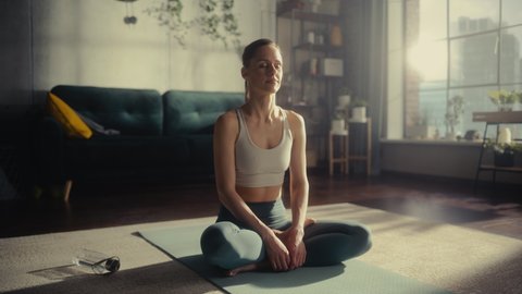 Young Athletic Woman Exercising, Practising Meditation in the Morning in Her Bright Sunny Home Living Room. Healthy Lifestyle, Fitness, Wellbeing and Mindfulness Concept.