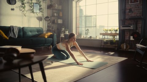 Young Beautiful Female Exercising, Stretching and Practising Yoga in the Morning in Her Bright Sunny Loft Apartment. Healthy Lifestyle, Fitness, Wellbeing and Mindfulness Concept.