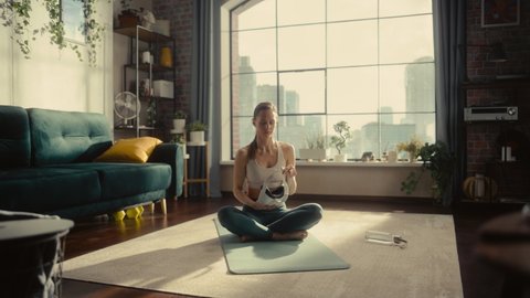 Young Athletic Woman Putting On Virtual Reality Headset, Practising Meditation in Modern Futuristic Way in Bright Sunny Home Living Room. Healthy Lifestyle, Fitness, Wellbeing and Mindfulness Concept.
