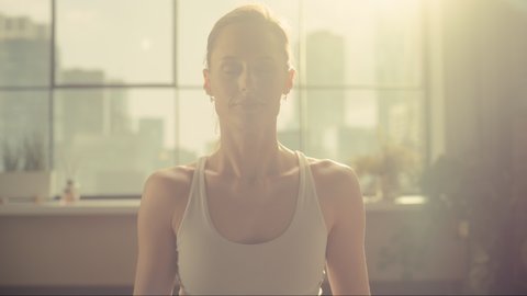 Close Up Portrait of a Young Beautiful Female Exercising, Practising Meditation in the Morning in Her Bright Sunny Loft Apartment. Healthy Lifestyle, Fitness, Wellbeing and Mindfulness Concept.