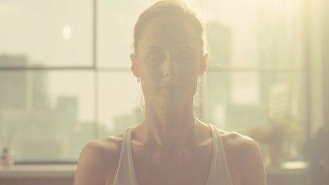 Close Up Portrait of a Young Athletic Woman Exercising, Practising Meditation in the Morning in Her Bright Sunny Home Living Room. Healthy Lifestyle, Fitness, Wellbeing and Mindfulness Concept.