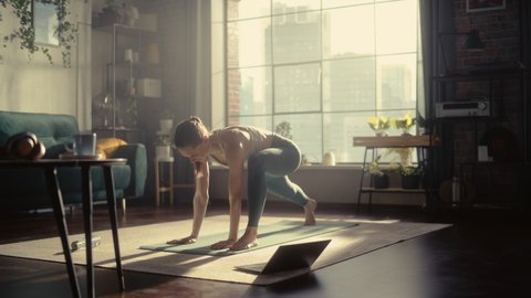 Portrait of a Happy Fit Young Woman Doing Stretching and Yoga Exercises During Morning Workout with Online Coach via Laptop Computer. Healthy Lifestyle, Fitness, Wellbeing and Mindfulness.