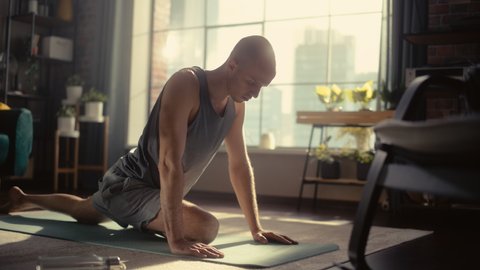 Young Athletic Man Exercising, Stretching and Practising Yoga in the Morning in His Bright Sunny Home Living Room. Healthy Lifestyle, Fitness, Wellbeing and Mindfulness Concept.