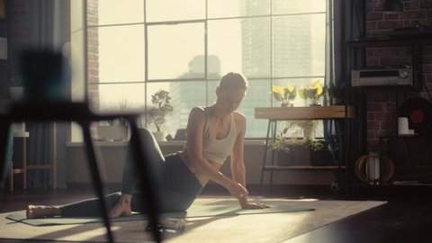 Young Athletic Woman Exercising, Stretching and Practising Yoga in the Morning in Her Bright Sunny Home Living Room. Healthy Lifestyle, Fitness, Wellbeing and Mindfulness Concept.