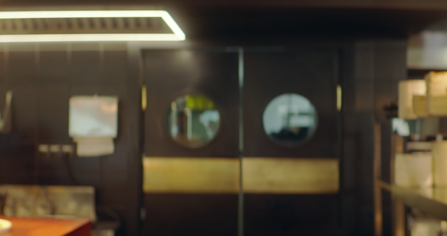 TRACKING Caucasian male chef walking into commercial restaurant kitchen through the swinging doors. Shot with 2x anamorphic lens | Shutterstock HD Video #1090365339