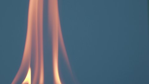 The wooden fire is orange, and the smoke of the fire from the mustard tree is on a dark blue background. Close-up of a flame with white smoke. Slow motion, 4K.