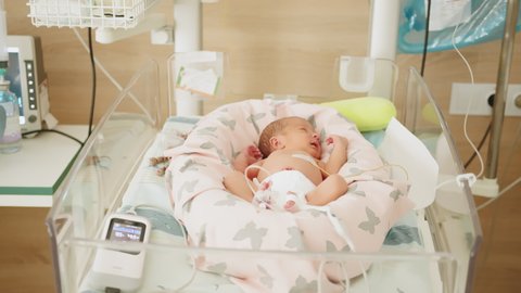 Two-day-old newborn baby in intensive care unit in a medical incubator. Newborn rescue concept. Premature newborn baby in the hospital incubator after c-section in 33 week. Hospital incubator