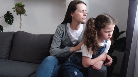 Worrying loving mother sitting on couch near upset little daughter, saying sorry. Young mom consoling sad preschool girl after quarrel, parent and child empathy, compassion. Family problems concept.